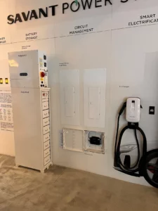 Wall with a Tesla charging station and electrical panel.